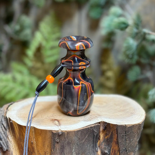 Lava orange and smokey silver swirls in obsidian black acrylic hand crafted on the lathe into a rabbit distress squealer with custom matching lanyard. Radiant orange highlights. The custom game call sits atop a wood stump with natural background.