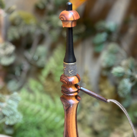 This caramel rosewood turkey trumpet as a dark buffalo horn mouth piece. The custom engraved collar shows brassy turkey foot prints and below it on the wood flute, a beaded lanyard.