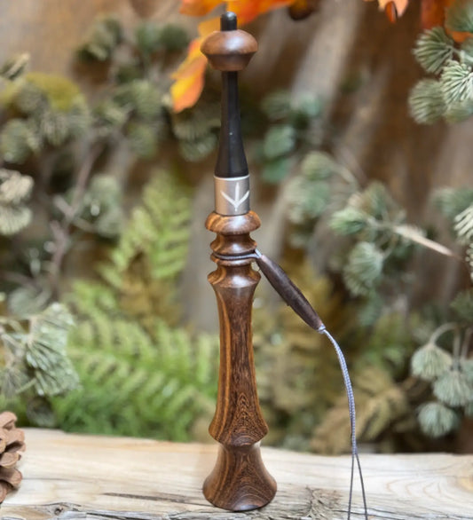 Brown Mora wood turkey trumpet with a lanyard and custom turkey print collar sitting upright on weathered wood platform.