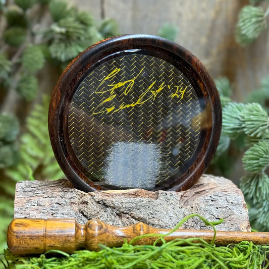 Cocobolo Turkey Call with glass surface and carbon fiber soundboard propped up behind lighter tone black locust striker in foreground