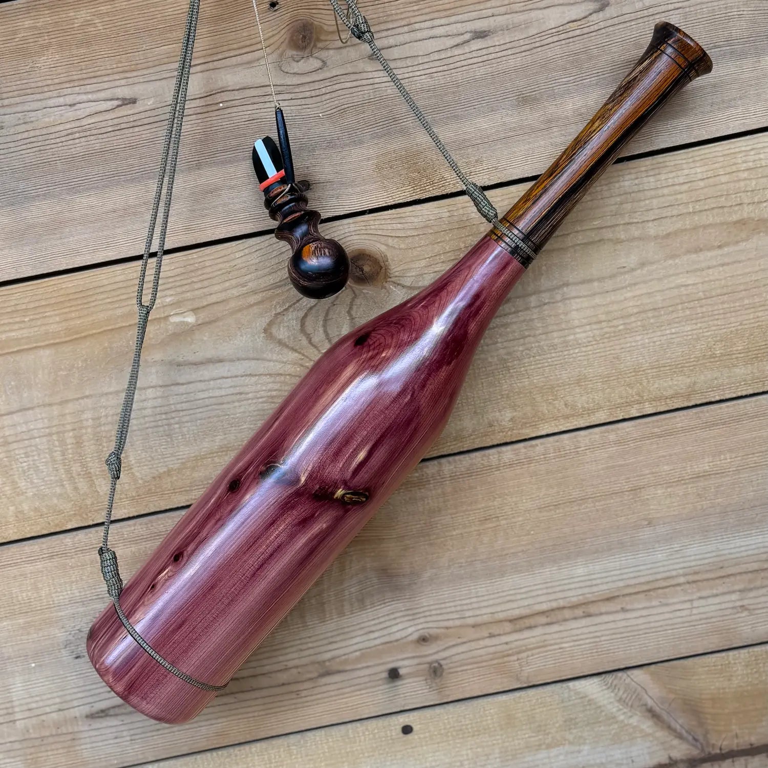 Eastern Red Cedar Bugle hanging on a wood wall with custom lanyard.