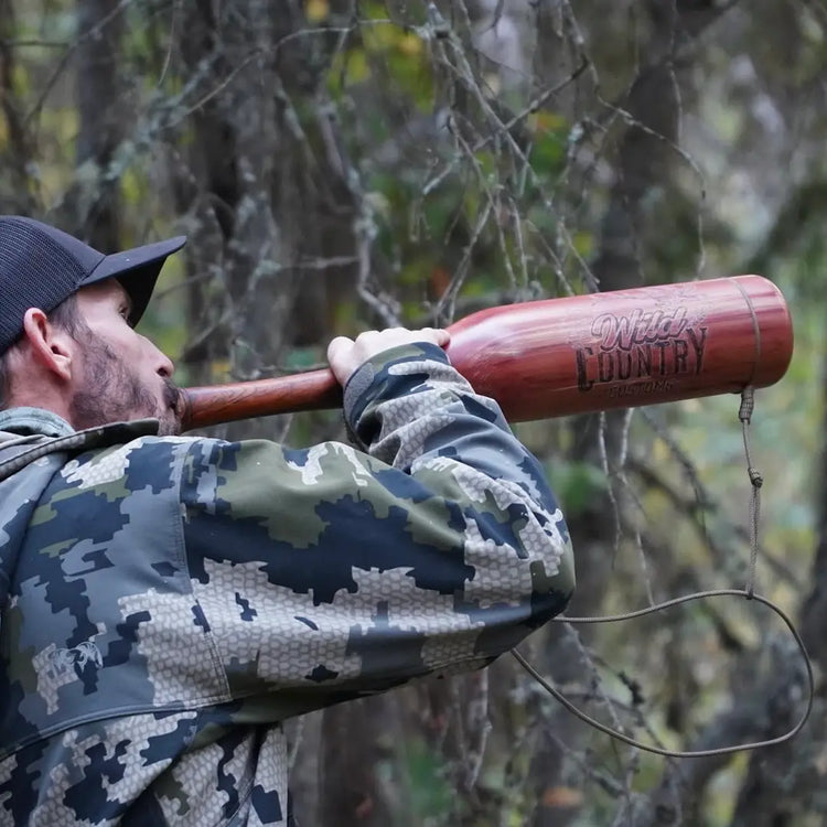 handcrafted red cedar bugle with cocobolo mouthpiece being actively played by hunter in the woods wearing camo