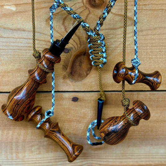 Bocote Predator Call Set with rabbit squealer, coyote howler, fawn distress bleat, and rodent squeaker hanging from a custom made lanyard woven with aqua blue and gold and black cords