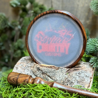 Bolivian Rosewood Turkey Call with frosted glass and Wild Country Customs logo in red propped up with matching striker in foreground