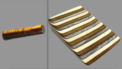 swatch of swirling copper tone acrylic rod next to Buckskin laminate wood pattern of alternating grey, copper, and creme tones separated by black dividing lines