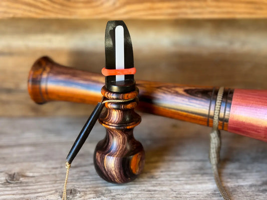 Cocobolo Cow Elk Call displayed with a Cocobolo wood mouthpiece of a larger elk bugle in the background 