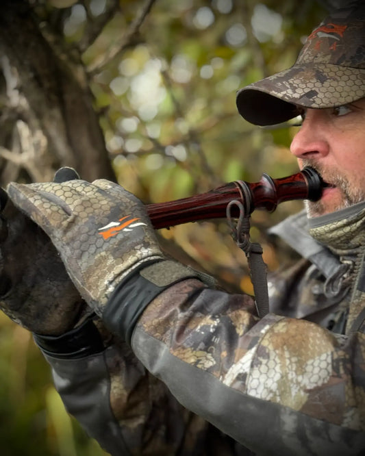 Cocobolo Goose flute being played in the field by hunter wearing gloves looking on