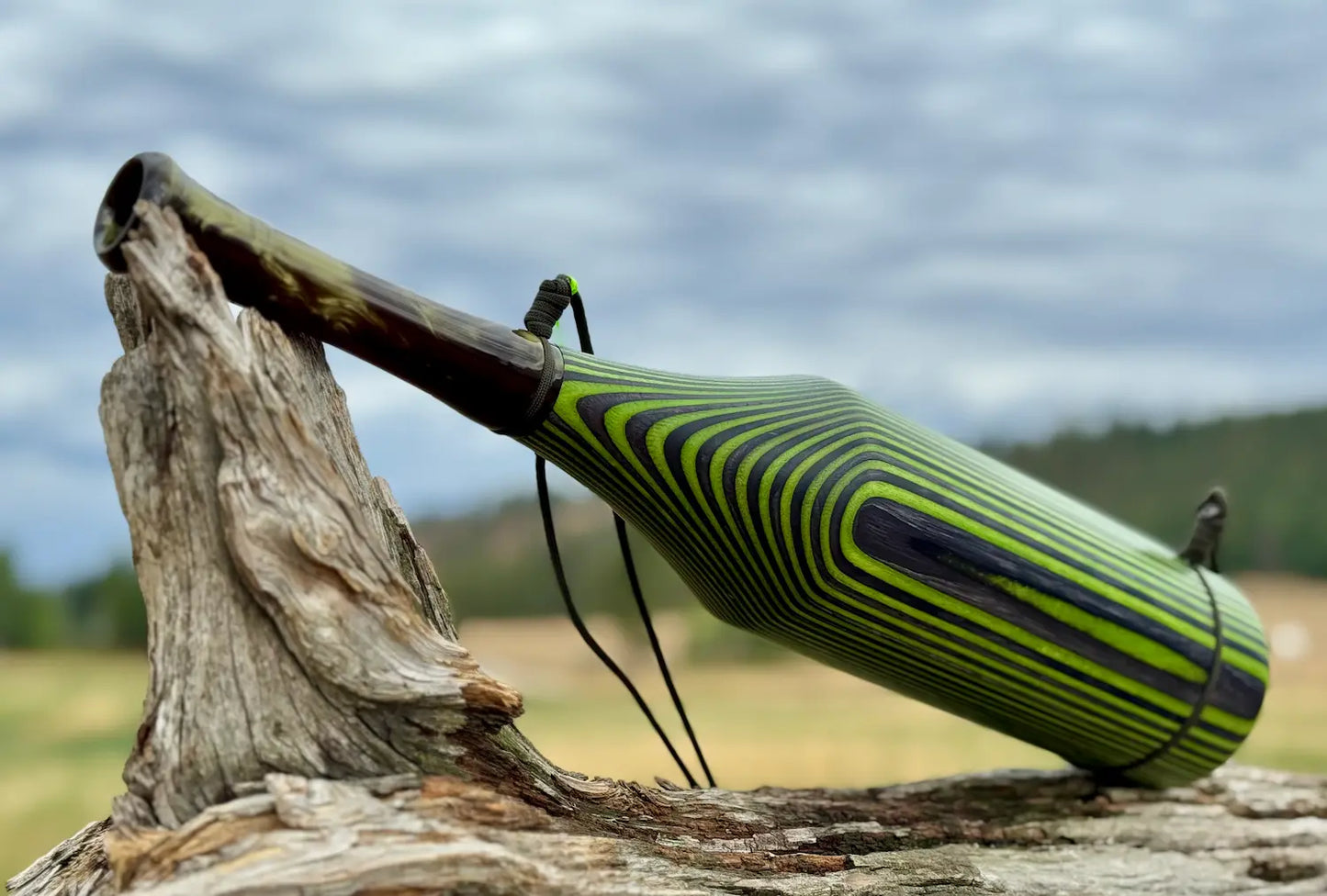 Venom Pearl Acrylic mouthpiece with Green Hornet Laminate Bugle tube on display with lanyard resting on a piece of driftwood