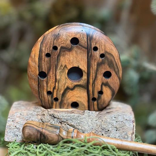 Gorgeous wood grain character shows deep black and golden wood grain in this mun ebony turkey pot call with unique hole pattern. The custom matching striker lays in the foreground.