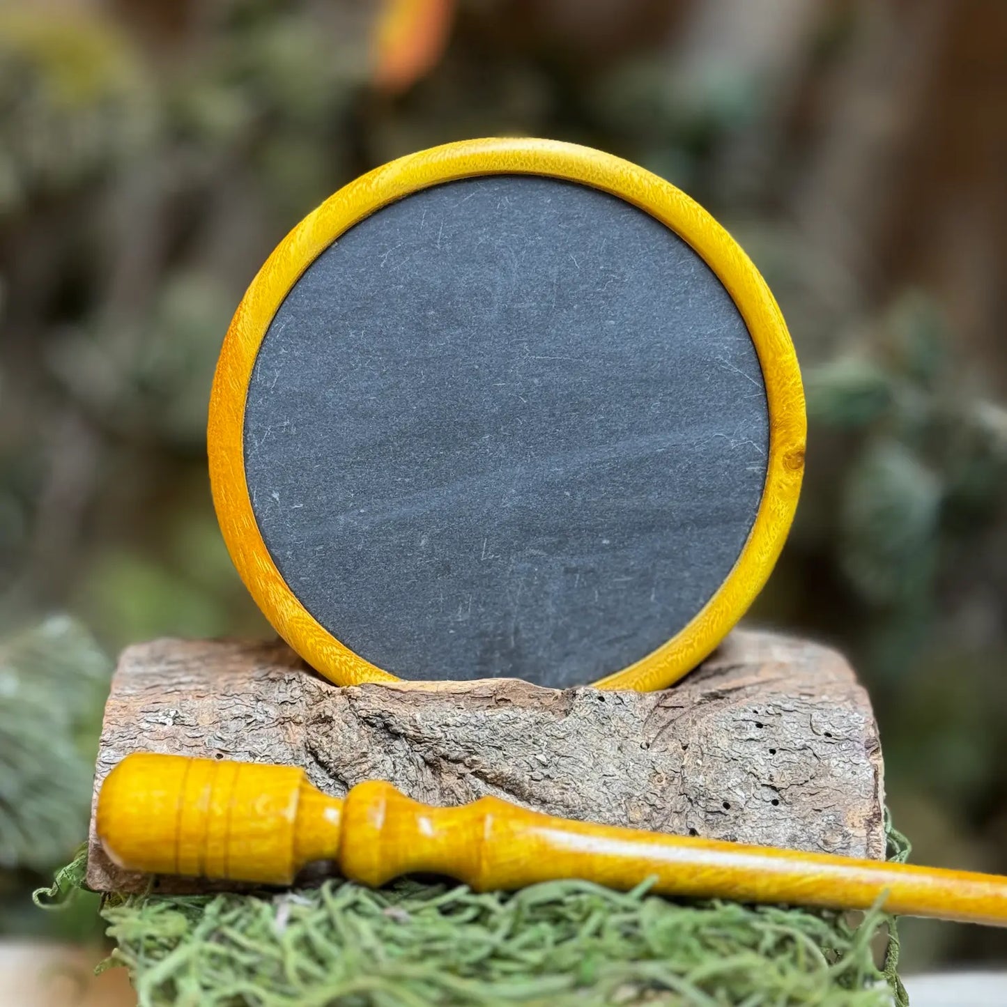 Golden osage wood radiant with bright orange or yellow hues sits upright on display showing black slate surface and matching osage striker in the foreground