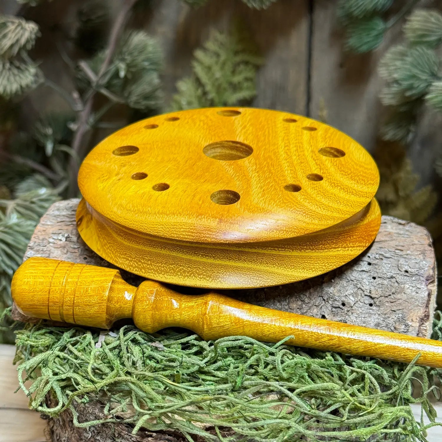 Golden osage wood radiant with bright orange or yellow hues sits showing ergonomic profile showing grooved edge perfect for resting the pot call in your hand with good  finger grip. A matching custom osage striker lays in the foreground