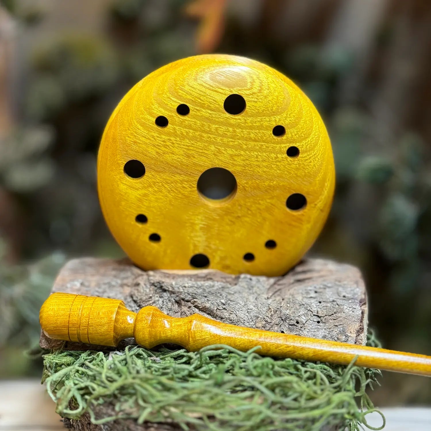 Golden osage turkey pot call shows radiant wood grain pattern across the pot call orb, a unique hole pattern trademark to Wild Country Customs, and the bright orange and golden hues give a sense of elegance. A matching custom osage striker lays in the foreground