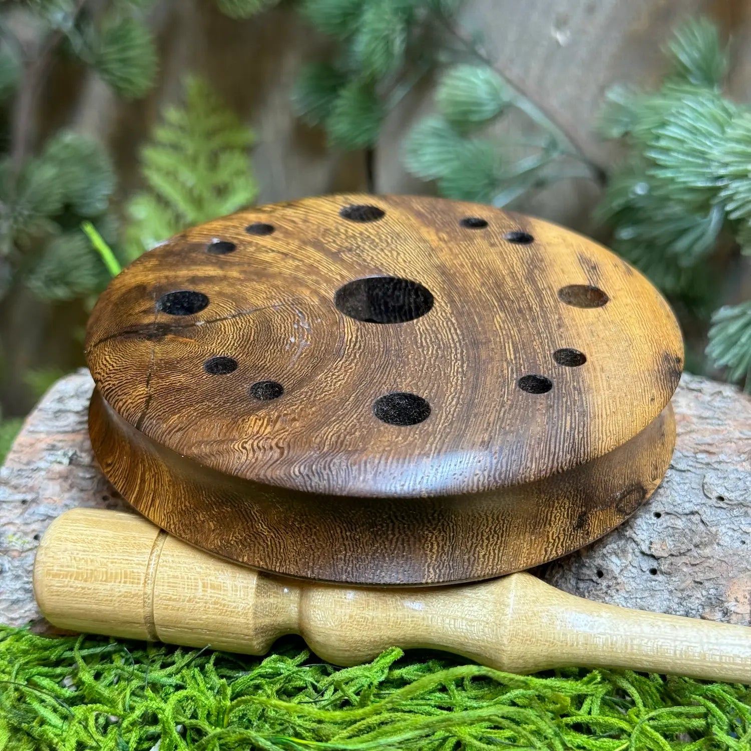 pheasantwood turkey pot call beautifully made with character in the wood grain seated atop a light toned black locust wood striker 