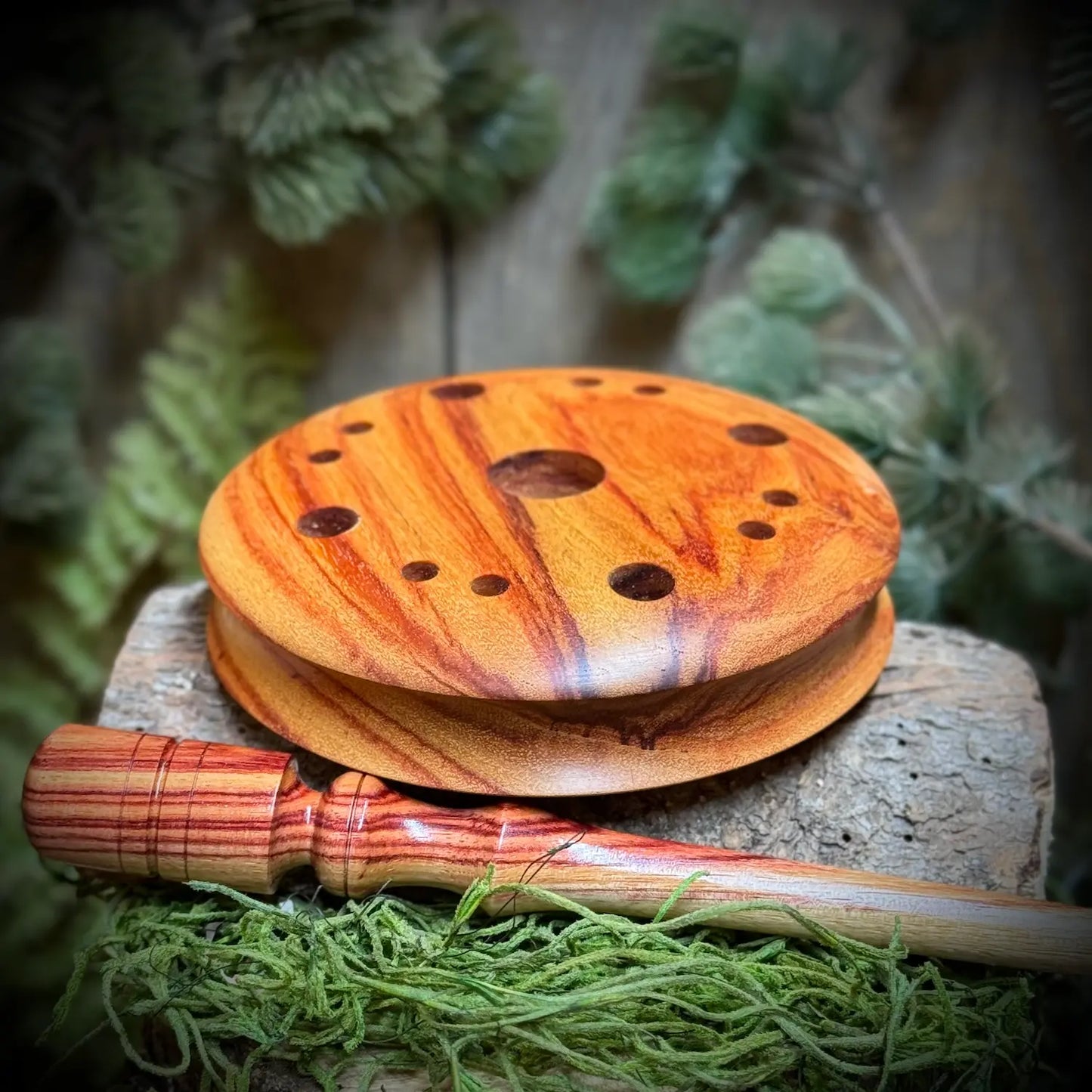 Tulipwood Turkey Pot Call set on it's side to show grooved edges atop a matching tulipwood striker
